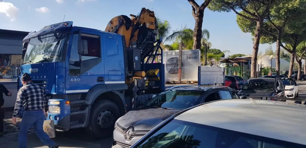 Mezzo con gru durante la movimentazione di un impianto di climatizzazione