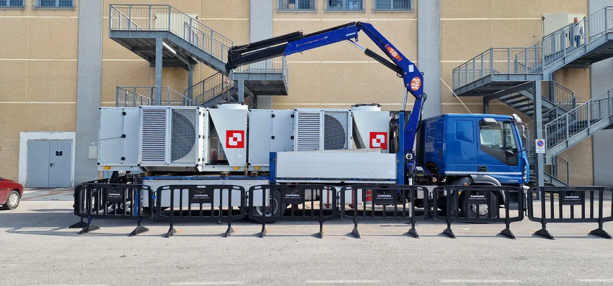 Gruppi frigo montati su un camion con gru davanti a un edificio industriale